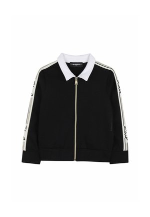 Chaqueta negra con cremallera, cuello blanco y rayas blancas con texto a lo largo de las mangas, colocada sobre un fondo blanco.