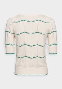 Kremowy sweter bawełniany z krótkimi rękawami, z zielonymi detalami w zygzak oraz żeberkowym wykończeniem. Teksturowany wzór dodaje wizualnego zainteresowania.