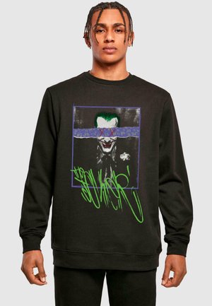 Black sweatshirt featuring a graphic of a clown-like figure with a green accent, framed with a purple box and graffiti-style text in green.