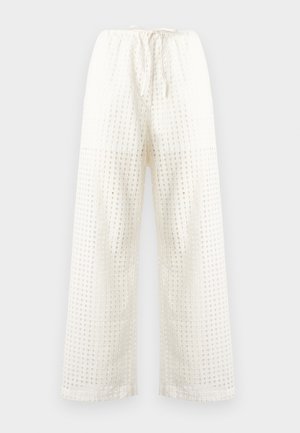 Pantalon ample couleur crème avec un motif carré texturé, doté d'une taille à cordon et d'une coupe ample. Le tissu semble léger et respirant.