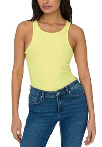 Top de tirantes amarillo de canalé con cuello redondo, combinado con unos jeans ajustados azules. El top tiene una tela texturizada y un ajuste ceñido.