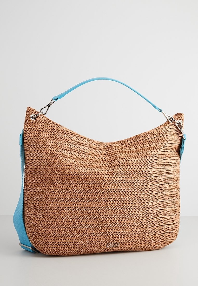 Sac à main en paille tressée marron avec une surface texturée, doté d'une bandoulière bleu clair et d'accents métalliques argentés.
