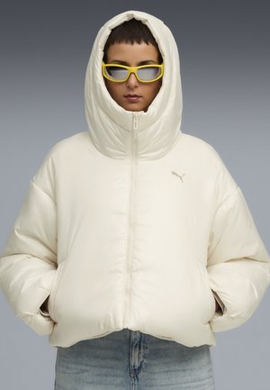 Pufferjack in off-white, met een hoge capuchon, ritssluiting en geribbelde manchetten. Vergezeld van gele rechthoekige zonnebril.