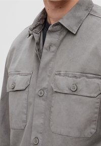 Grijs katoenen overhemd met knopen, voorzien van twee borstzakken, een omgeslagen kraag en een gladde structuur met een subtiele glans.