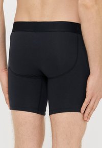 Fekete elasztikus anyagból készült boxeralsó sima derékpánttal, varrásmentes kialakítással és kontrasztos varrással, alkalmas mindennapi viseletre.