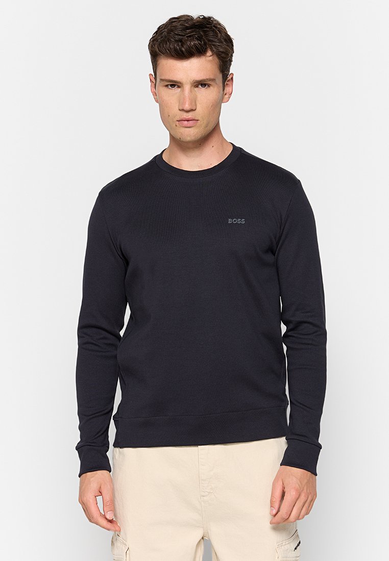 Sweatshirt col rond bleu marine en tissu côtelé, avec des manches longues et un petit logo brodé sur la poitrine. Texture douce, coupe décontractée.
