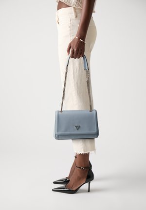 Light blue textured handbag with a chain strap, rectangular design, and triangular logo. Worn with cream pants and black pointed heels.