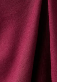 Hlboká fialovo-ružová látka s viditeľnou textúrou tkania, jemne zložená, vytvárajúca mäkké tiene a zvýraznenia.
