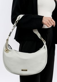 Borsa hobo bianca in pelle con forma curva, dotata di dettagli in metallo dorato e una catena sul manico regolabile.