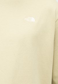 Μπεζ μακρυμάνικη μπλούζα από μαλακό ύφασμα. Διαθέτει μικρό λευκό λογότυπο "The North Face" στο στήθος. Απλός σχεδιασμός.