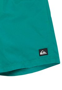 Turbansvarta badshorts av lättviktsmaterial, med en sydd fåll och en svart logotag med ett vitt emblem.