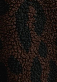 Fuzzy stof met een patroon van bruin en zwart die contrasterende kleuren vertonen, met een luxe textuur en diepte in het ontwerp.