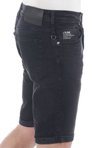 Shorts de mezclilla negra con corte recto, dobladillos enrollados, cinco bolsillos y un parche de cuero en la cintura trasera.
