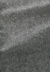 Visgraatpatroon stof in grijstinten met een gestructureerde afwerking, die een subtiele glans en een zachte, vloeiende val vertoont.
