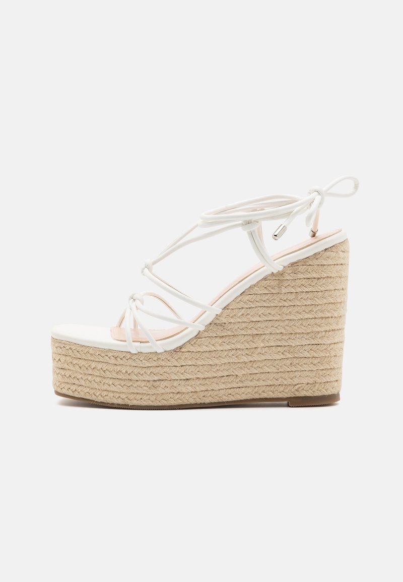 Sandale compensée blanche à lanières avec plateforme en jute tressé de style espadrille et fermeture à nouer à la cheville, vue de profil sur fond blanc.