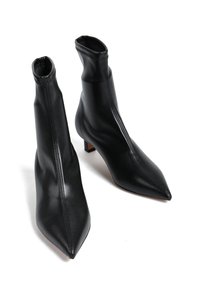 Czarne skórzane botki za kostkę o dopasowanej formie, z noskiem w szpic i niskim kwadratowym obcasem. Posiadają kontrastowe szwy z przodu oraz zamek błyskawiczny.