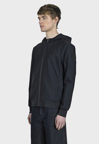 Černá mikina na zip vyrobená z hladké, lehké tkaniny, s kapucí, bočními kapsami a žebrovanými manžetami. Jednoduchý a moderní design.