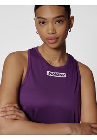 Fioletowy bezrękawnik sportowy z okrągłym dekoltem i białym logo "HUMMEL" na piersi. Gładki, elastyczny materiał zaprojektowany do ruchu.