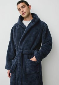 Granatowa sz hoodie z pluszowego materiału o teksturowanym geometrycznym wzorze, posiada pasek wiązany i przednie kieszenie.