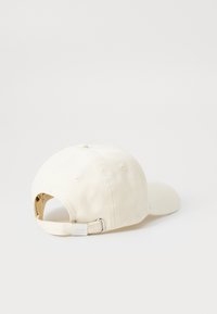 Fehér pamut baseball sapka ívelt karimával, állítható pánttal fém csattal, és varrási részletekkel a hátsó részen.