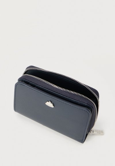 Πορτοφόλι σε ναυτικό μπλε χρώμα από δέρμα με υφή, δύο θήκες με φερμουάρ και μικρή ασημένια λεπτομέρεια λογότυπου μπροστά.