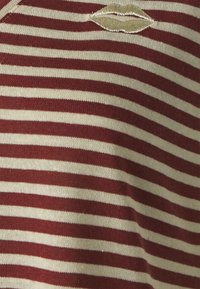 Pasiasty sweter w kolorze burgundowym i kremowym, z haftowanym motywem ust. Miękka faktura z wąskimi poziomymi paskami.