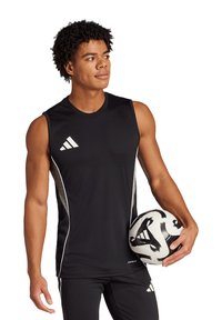 Canotta sportiva nera senza maniche con dettagli bianchi e logo Adidas; il modello tiene in mano un pallone da calcio bianco e nero, indossando pantaloni sportivi neri.