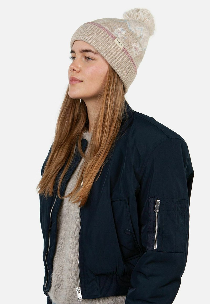 Navy bomber jacket with a zip closure and ribbed cuffs, paired with a beige knitted beanie featuring a pom-pom and colorful patterns.
