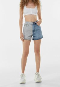 Denimshortsit, joissa vaalea tummaan liukuväri, korkea vyötärö, käännetty helma, etutaskut ja nappisuljenta. Yhdistetty valkoisen lyhyen topin kanssa.