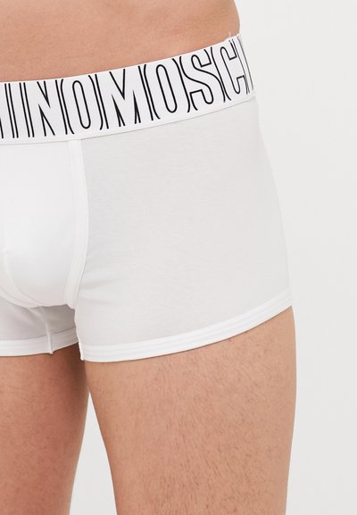 White cotton boxer shorts with a black logo waistband, featuring a smooth texture and fitted design, showcasing a simple and minimal pattern.
