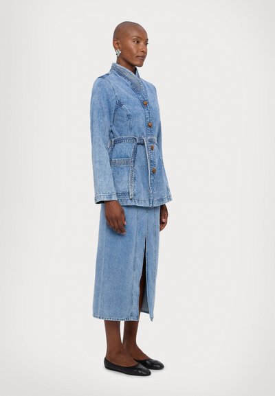 Denimjakke og skjørt sett i lyseblått, med en tettsittende design, høy krage, knappelukking, bånd i midjen og splitt på siden av skjørtet.