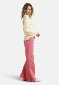 Cream ribbed knit sweater with balloon sleeves paired with light pink wide-leg pants and white sneakers, set against a plain background.