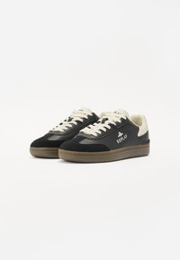 Baskets noires et beiges en matériaux de suede et de cuir, à bout rond, avec des lacets contrastants et un détail de logo sur le côté. Semelle en caoutchouc avec un motif antidérapant.