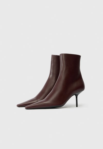 Botas de cuero burdeos hasta el tobillo con puntera puntiaguda y tacón de aguja. Textura suave y diseño minimalista. Sin herrajes ni acentos visibles.