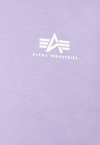 T-shirt viola chiaro in cotone, con un logo bianco e strisce sul davanti. Texture liscia, design classico con collo a giro.