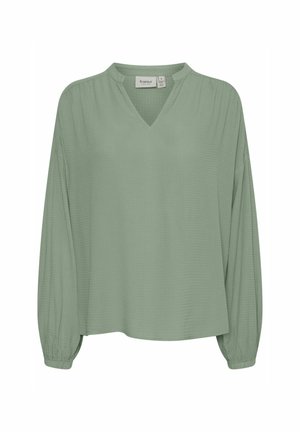 Blusa a maniche lunghe verde chiaro con scollatura a V e tessuto texturizzato. Caratterizzata da una vestibilità rilassata e polsini arricciati.