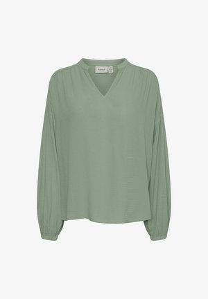 Hele roheline pikakätine pluus V-kaelusega ja tekstureeritud kangast. Omab lõdva sobivust ja kokku pandud mansette.