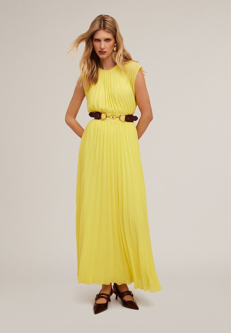 Abito lungo plissettato giallo con maniche a palloncino, vita cintrata e una cintura marrone. L'abito presenta una texture liscia e una silhouette fluttuante.