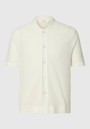 Polo en maille blanche à manches courtes avec patte boutonnée et motif texturé, conçu pour un usage décontracté.