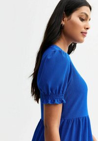 Abito blu a maniche corte con tessuto testurizzato, maniche a sbuffo e vita arricciata. Design semplice e fluido con scollatura rotonda.