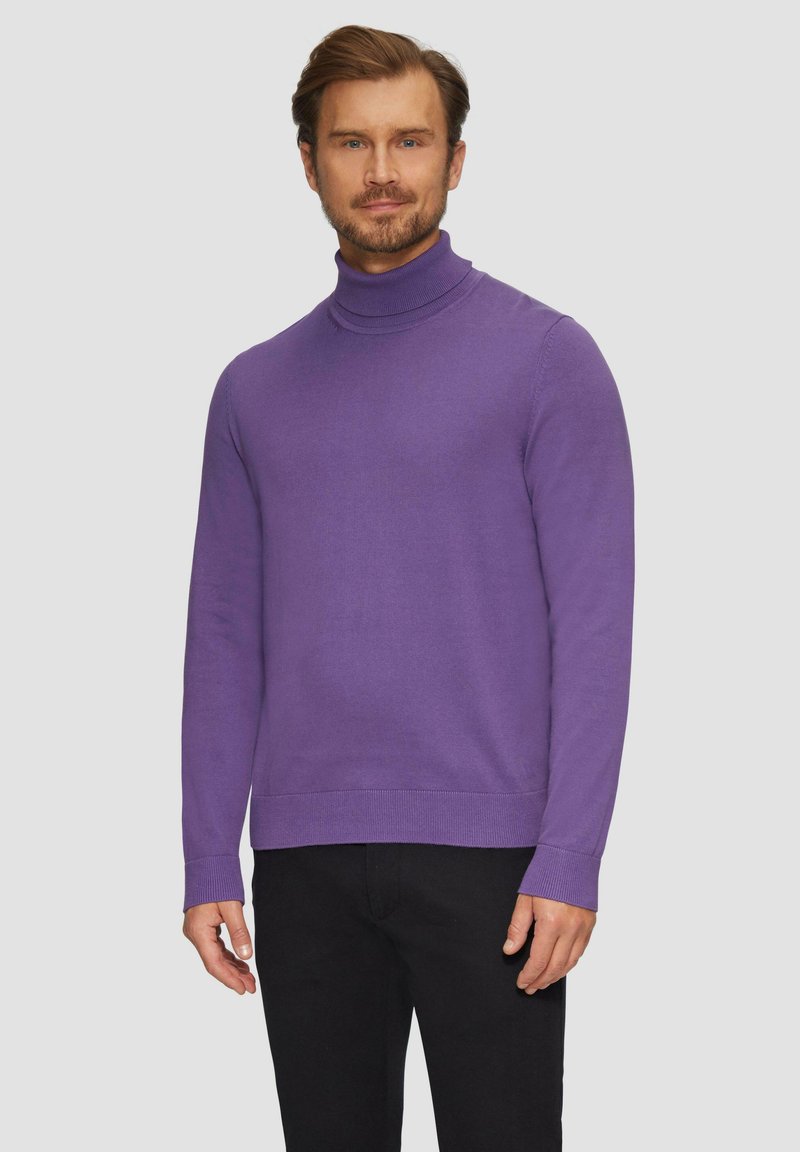 Paarse coltrui gemaakt van zachte brei, met een aansluitend ontwerp, geribbelde manchetten en onderrand, gedragen met zwarte broek.