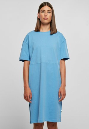 Robe T-shirt en coton bleu avec des manches courtes, coupe décontractée, fentes sur les côtés et accent étiquette verte. Texture lisse et design simple.