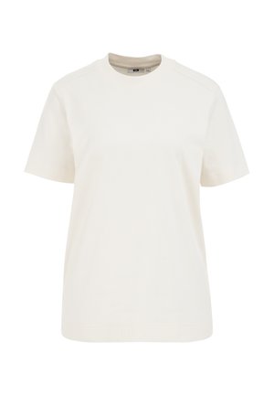 Kortärmad t-shirt i ljus krämfärgad bomull, med rund halsringning, avslappnad passform och subtila sömdetaljer på axlarna.