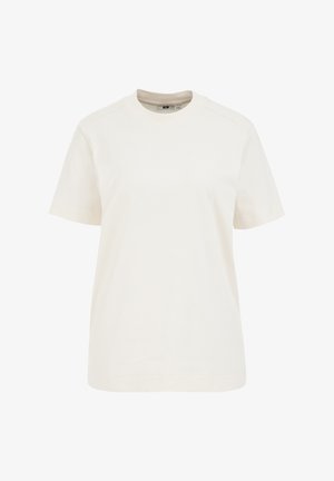 Krátky rukáv tričko z ľahkého krémového bavlny, s okrúhlym výstrihom, voľným strihom a jemnými švami na pleciach.