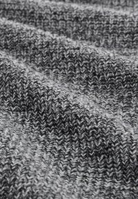 Close-up van een grijs en zwart gebreide stof met een ribbelstructuur en zachte plooien.