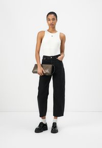 Hvit tettsittende body, høyde-justerte svarte vide jeans, grå clutch-veske, svarte kraftige sko, og ankel-lange hvite sokker.
