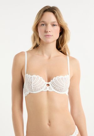 Weißer Spitzen-BH mit Blumen- und Muschelmotiven, ausgestattet mit verstellbaren d ünnen Trägern und einem zentralen Schlüsselloch-Detail. Glatte Textur, wellenförmige Kanten.