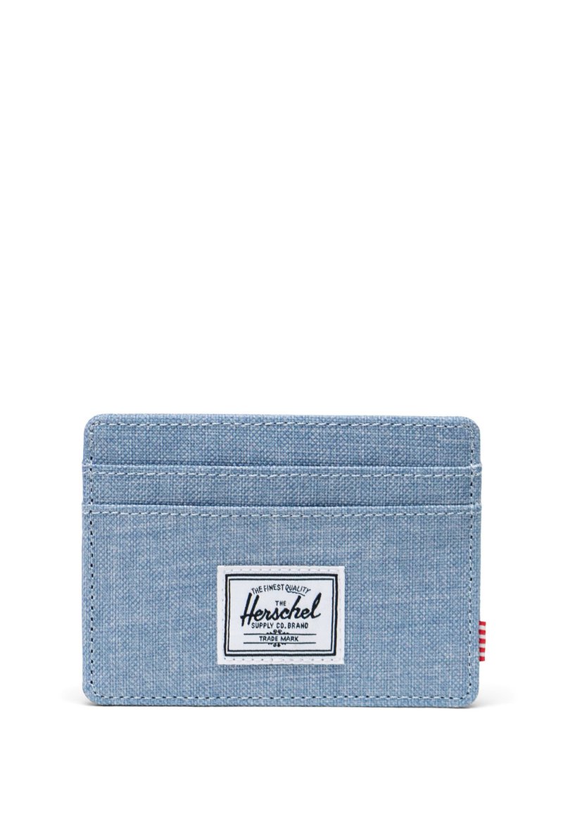 Jasnoniebieski materiałowy portfel na karty z trzema miejscami na karty i białą prostokątną etykietą marki Herschel na środku.
