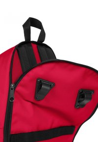 Mochila roja con una abertura con cremallera, que presenta correas y clips negros en su interior. El exterior tiene una textura suave con un material de tela duradero.