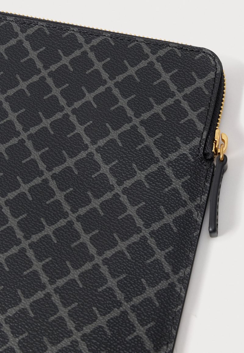 Bolso texturizado negro con un patrón geométrico gris, herrajes dorados en la cremallera y un tirador de cremallera negro contrastante.